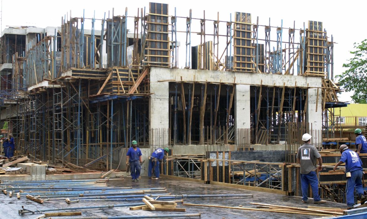 Trabalhadores da construção civil em obra com capacete e equipamentos de segurança